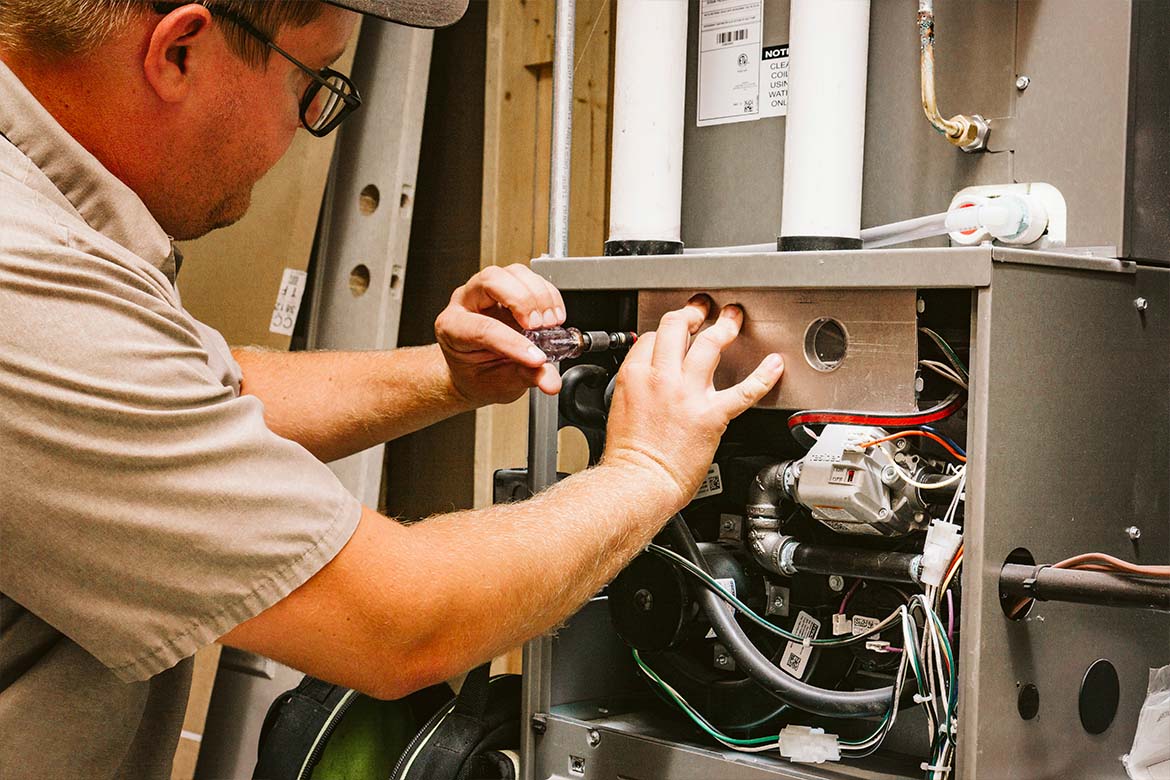 worker fixing a thermostat in a Milton, WI house on a wall